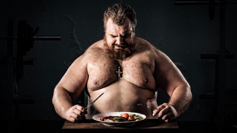 Shirtless muscular man eating a nutritious meal, symbolizing strength and health.